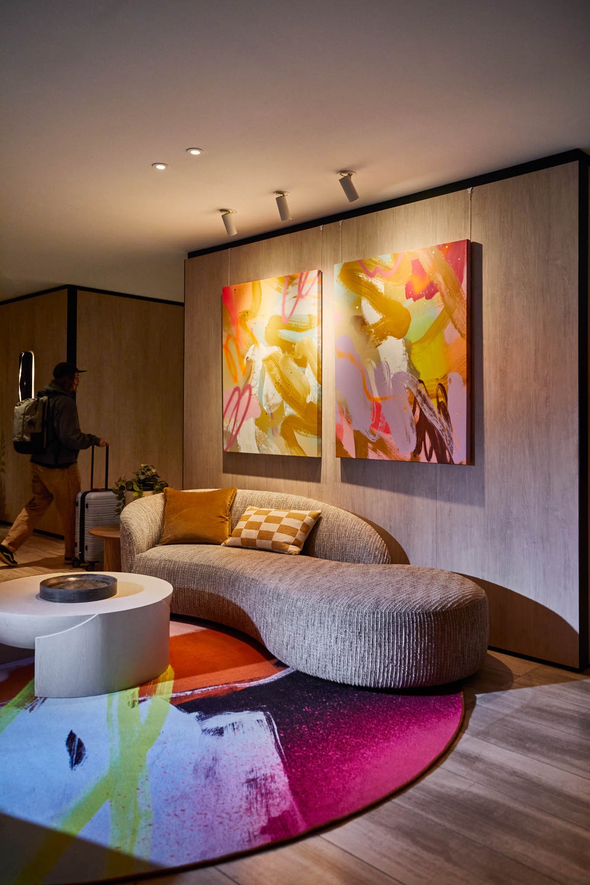 Modern hotel lobbt with a curved sofa, colorful abstract rug, and abstract wall art.